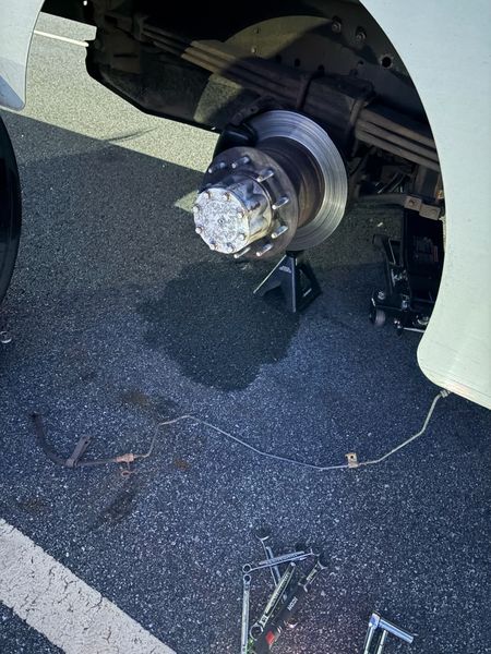 Box truck front hub and rotor with the wheel off and the old brake line on the ground