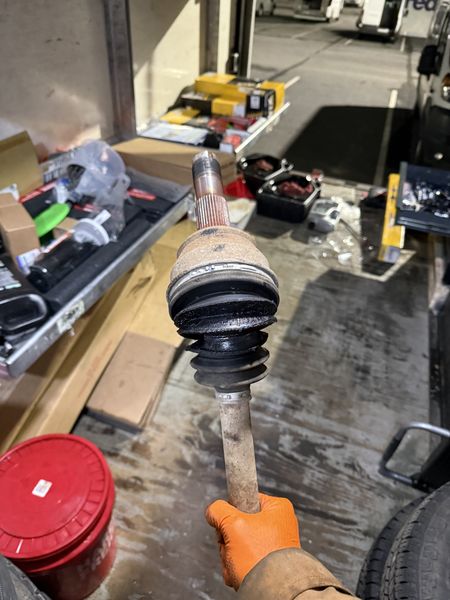 Technician holding a removed CV axle